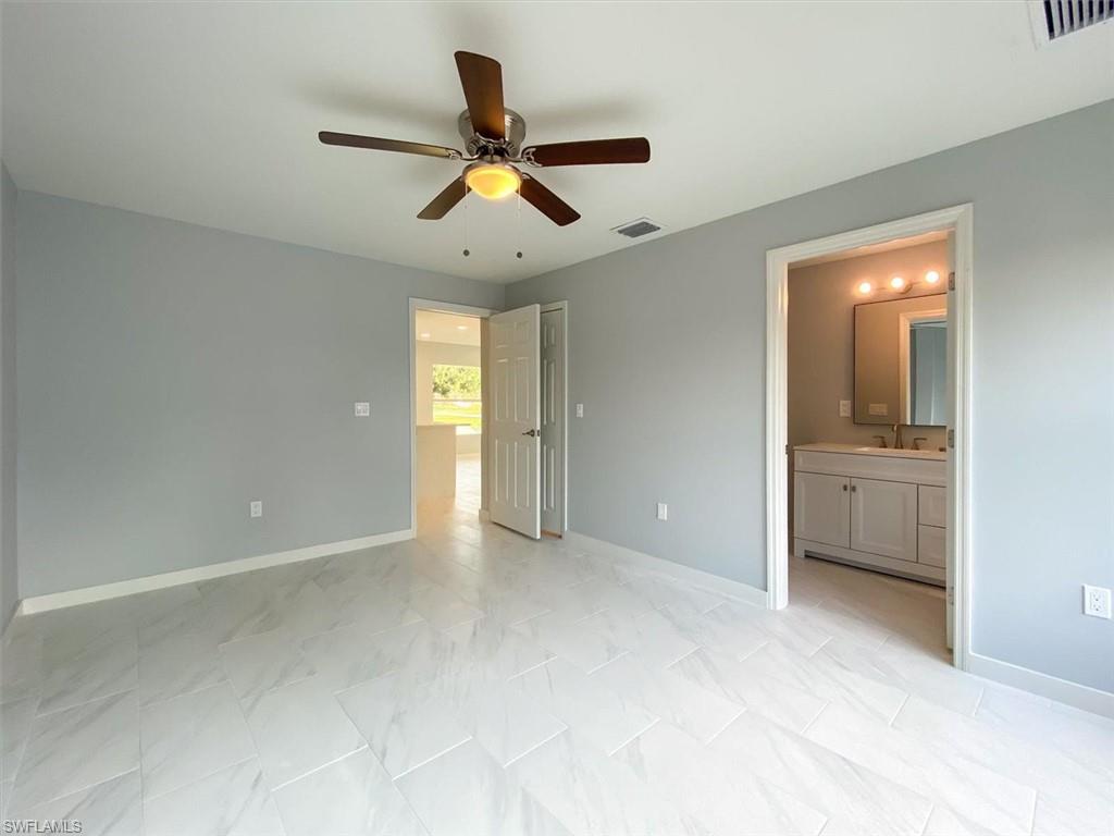 Unfurnished bedroom with ensuite bath and a ceiling fan