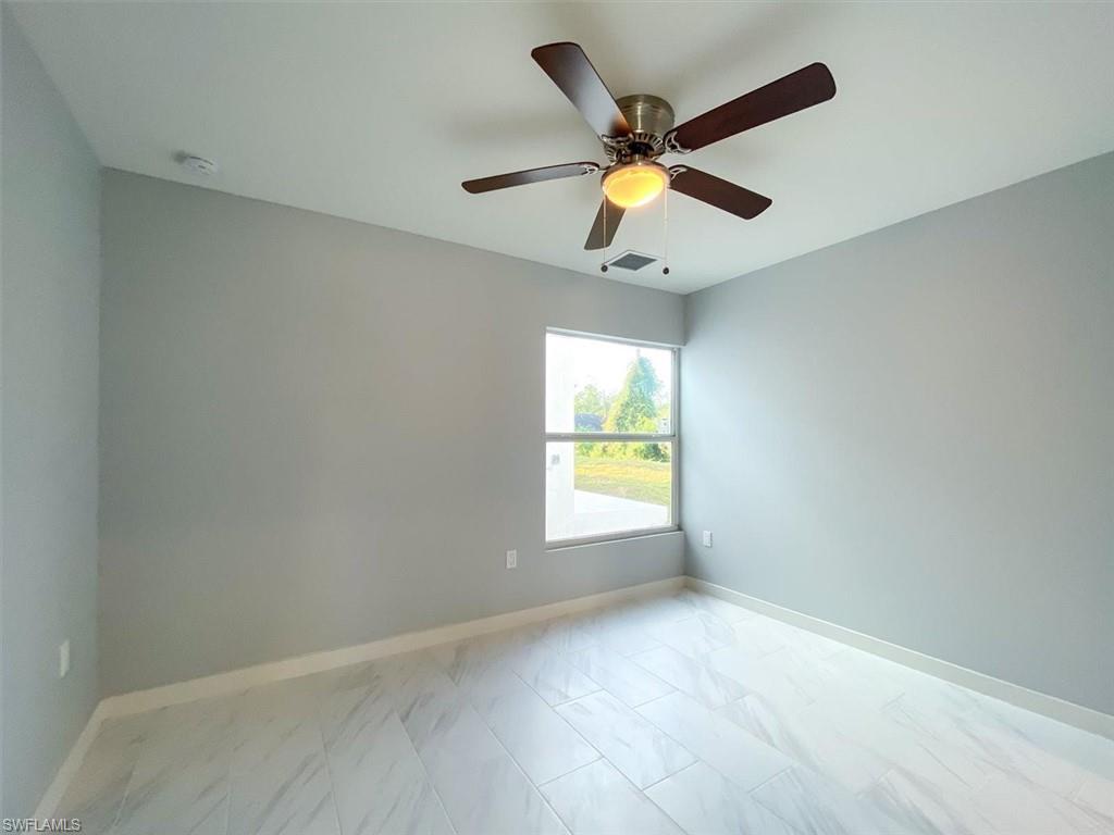 Unfurnished room with light marble finish floors and ceiling fan