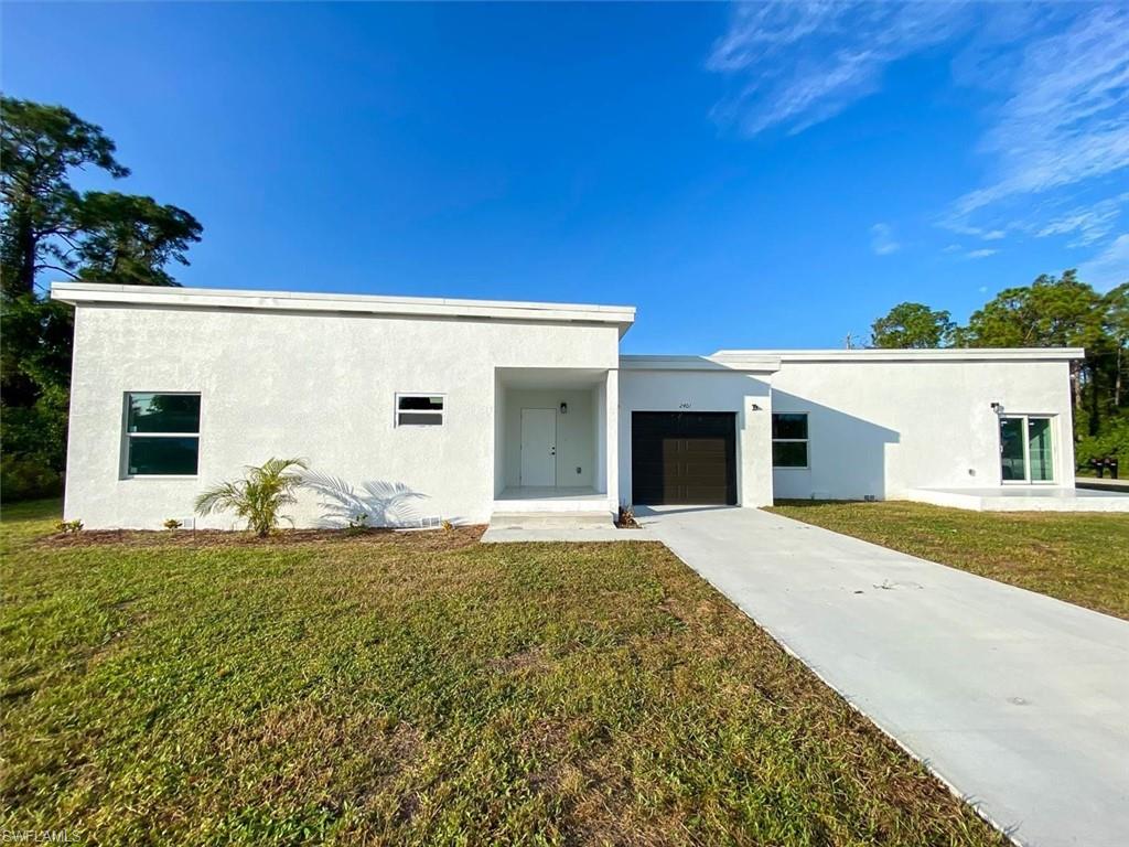 Contemporary home with stucco siding, a front yard, driveway, and an attached garage