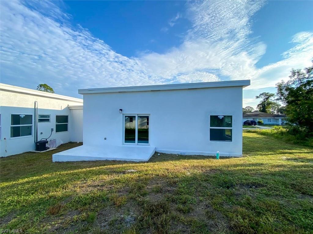 Rear view of property with stucco siding, a patio area, and a lawn