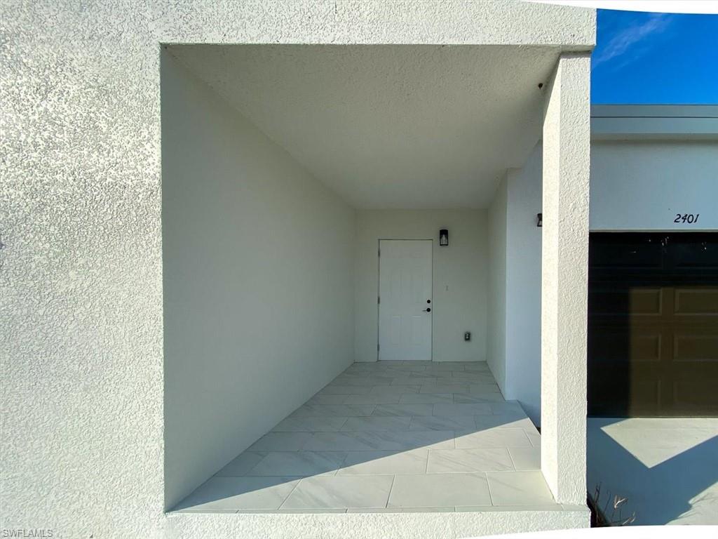 Property entrance featuring a patio, stucco siding, and a garage