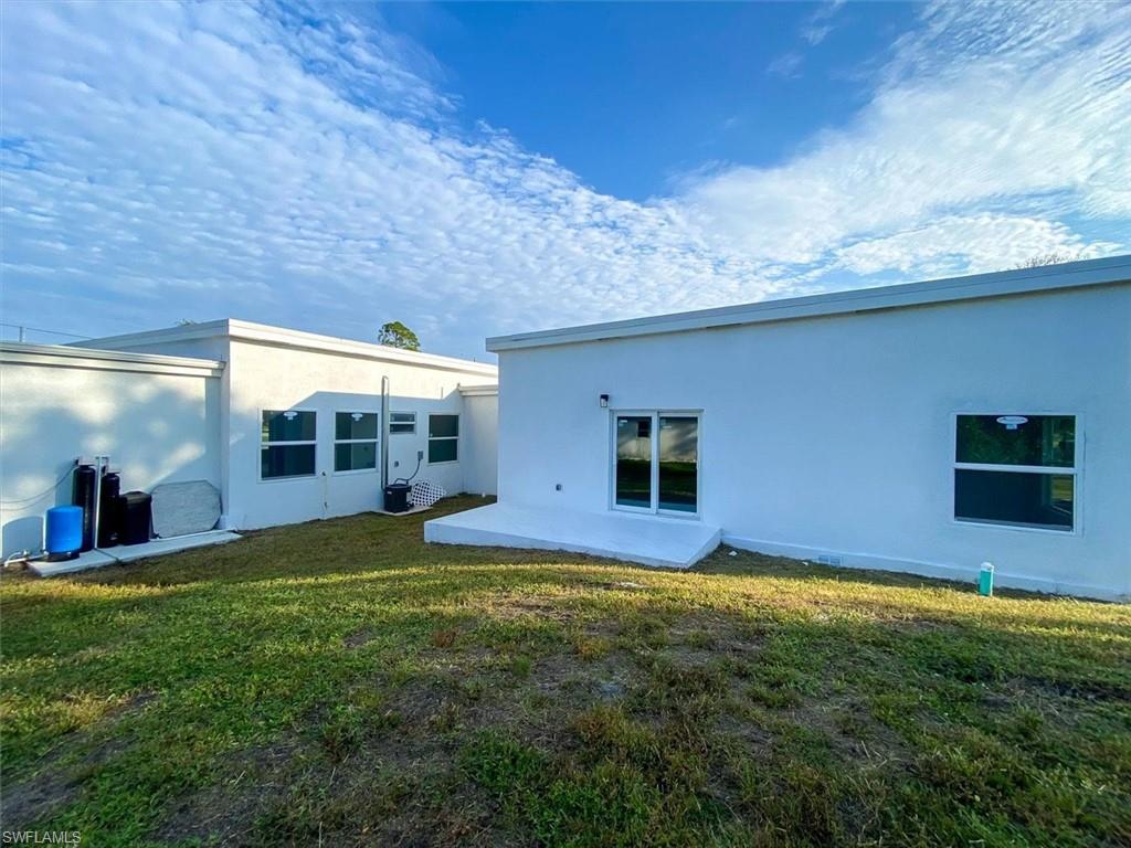 Back of property with a patio, a lawn, and stucco siding
