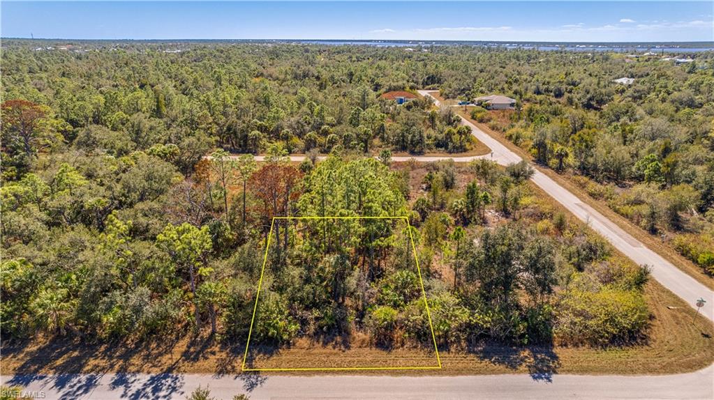 Aerial view of property and surrounding area with a heavily wooded area and property parcel outlined