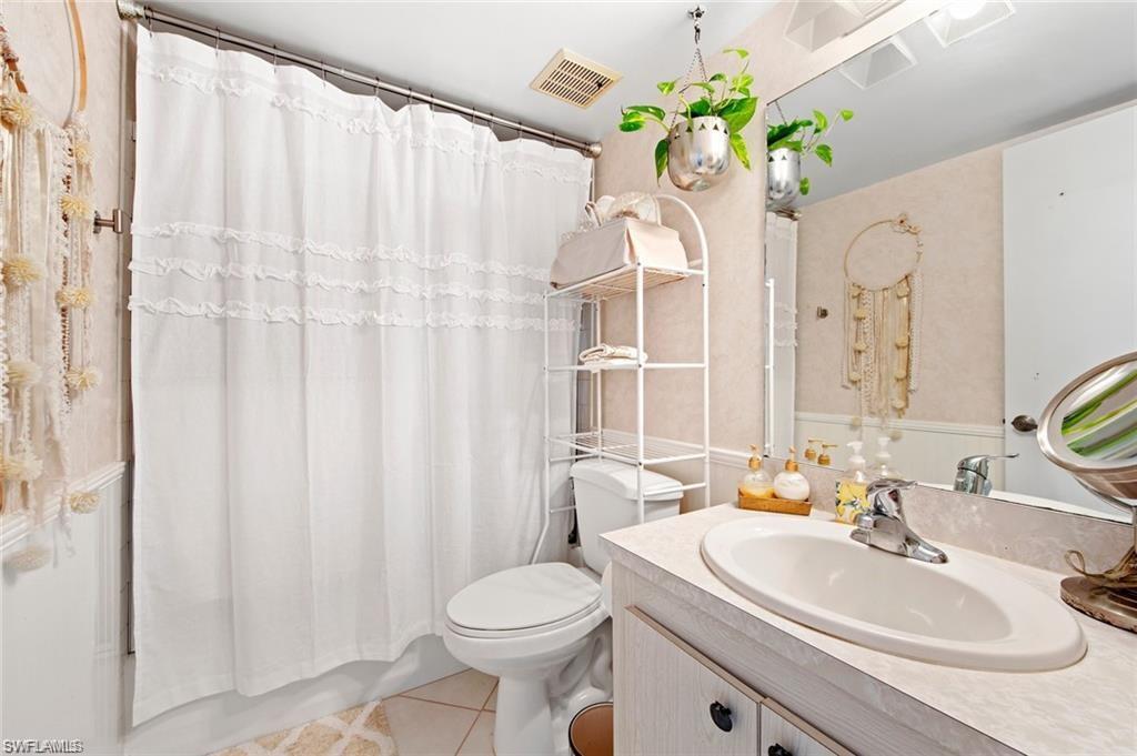Full bath with vanity, light tile patterned flooring, and shower / bath combo with shower curtain