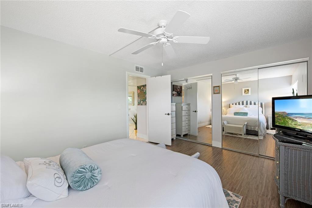 Bedroom featuring multiple closets, wood finished floors, a textured ceiling, and a ceiling fan