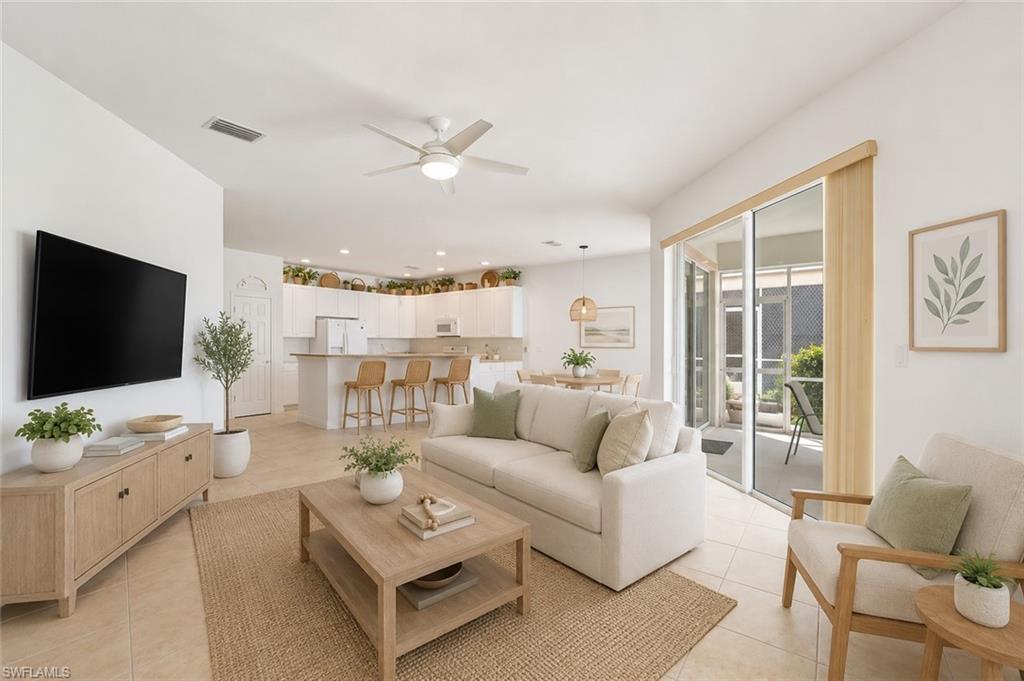 VIRTUALLY STAGED Open-concept living area featuring tile flooring, a ceiling fan, and sliding glass doors leading to an outdoor space
