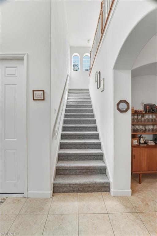 Stairway featuring a high ceiling and tile patterned floors