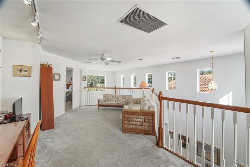 Living area with light colored carpet, track lighting, and a ceiling fan