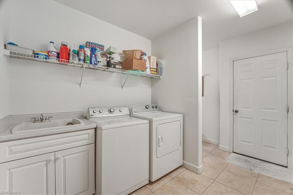 Laundry area featuring washer and dryer, light tile patterned floors, and cabinet space