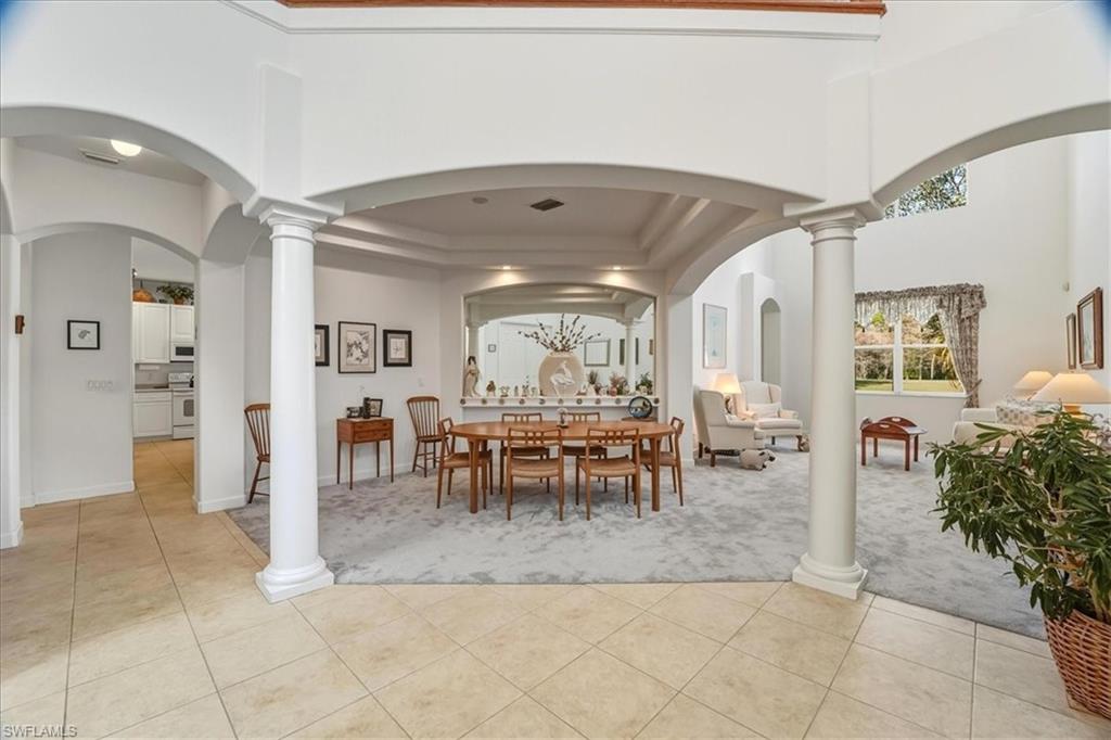 Dining area featuring arched walkways, decorative columns, light tile patterned floors, and a high ceiling