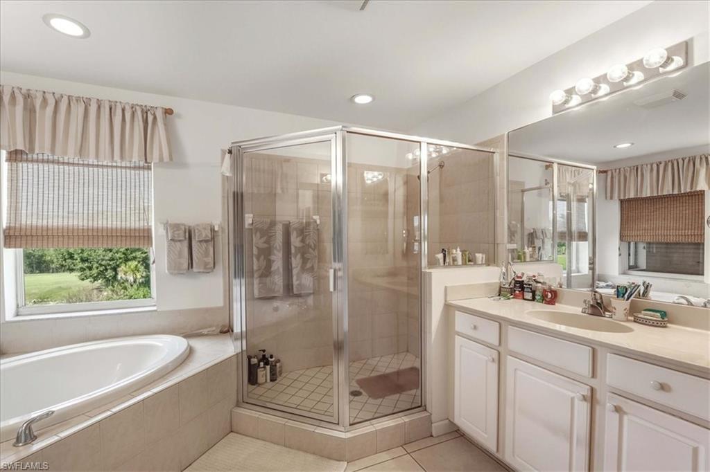 Bathroom featuring vanity, a shower stall, a bath, light tile patterned flooring, and recessed lighting