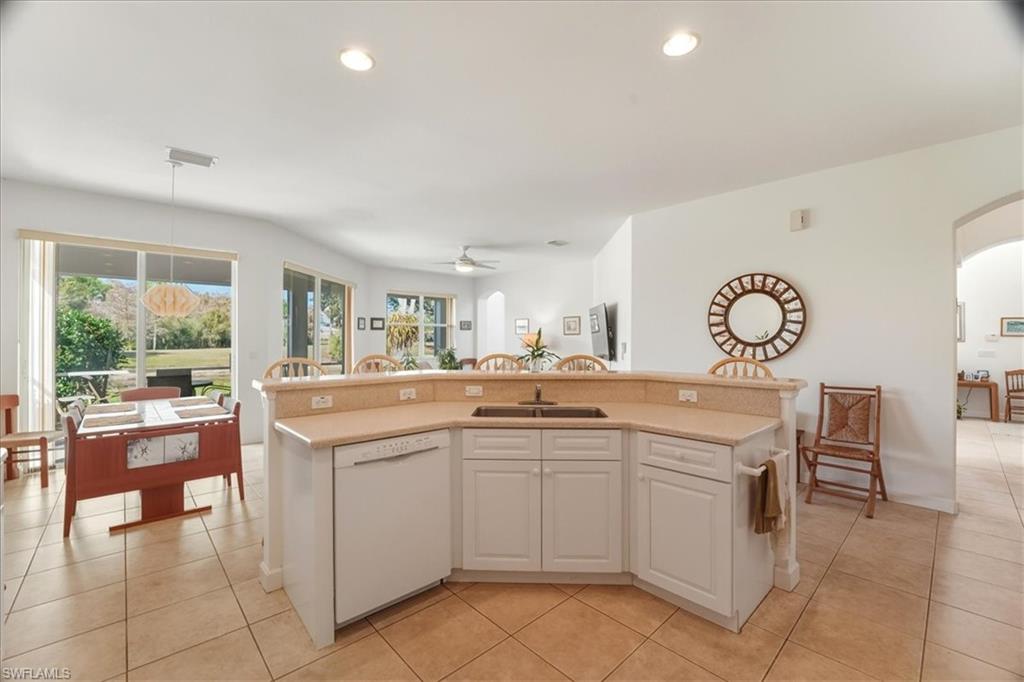 Kitchen with white cabinets, dishwasher, an island with sink, light tile patterned flooring, and recessed lighting