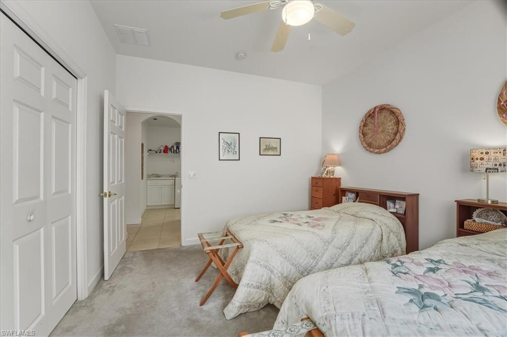 Bedroom with a closet, carpet floors, ceiling fan, and arched walkways