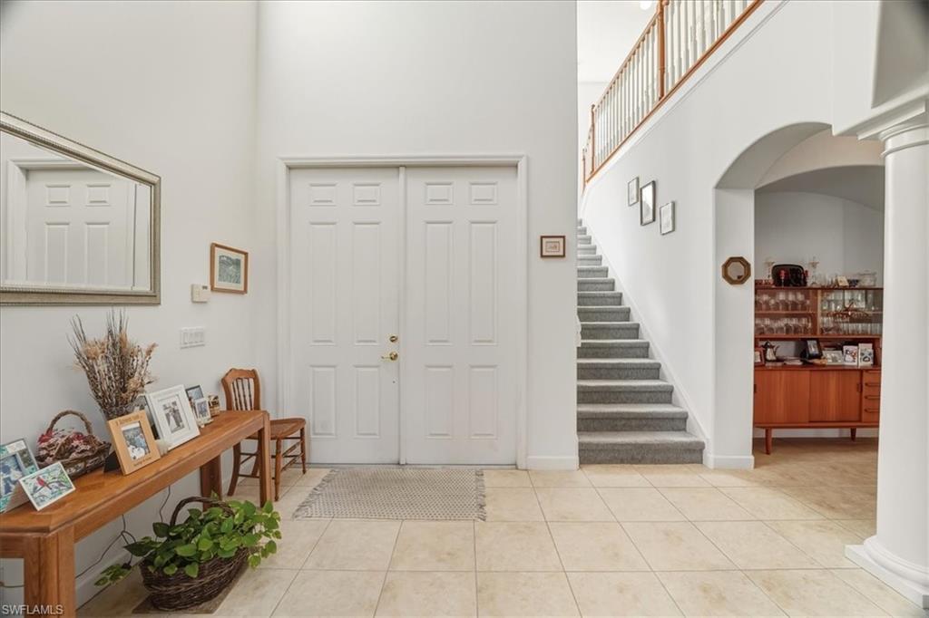 Foyer entrance with a high ceiling, light tile patterned flooring, arched walkways, and ornate columns