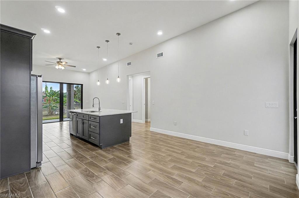 Kitchen featuring pendant lighting, a center island with sink, recessed lighting, wood tiled floors, and ceiling fan