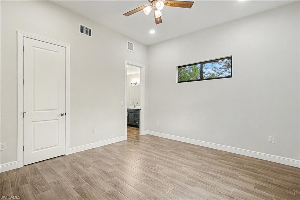Unfurnished bedroom with wood finish floors, ceiling fan, and connected bathroom