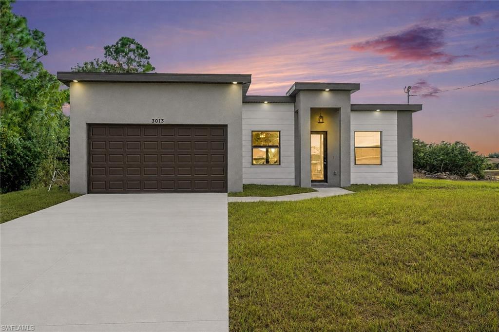 Contemporary exterior with a flat roofline, integrated garage, concrete driveway, and recessed exterior lighting
