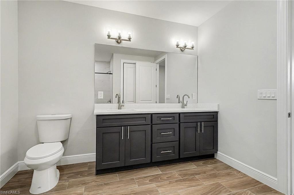 Bathroom featuring double vanity, wood finish floors, and a shower stall
