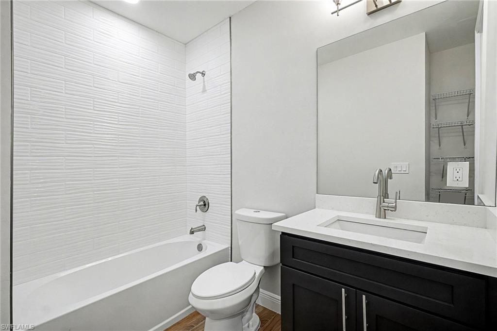 Bathroom with vanity, shower / washtub combination, and dark wood-style floors