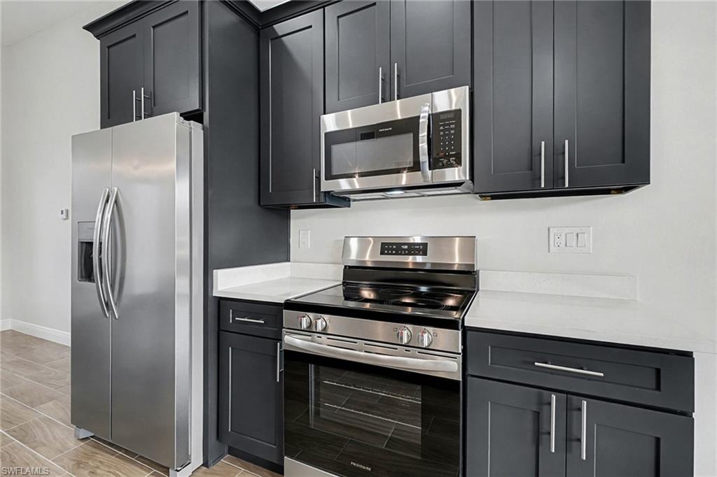 Kitchen featuring appliances with stainless steel finishes and light stone counters