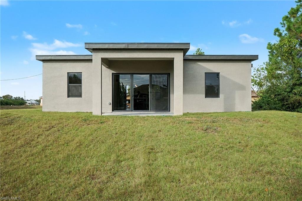 Rear view of property with a yard and stucco siding