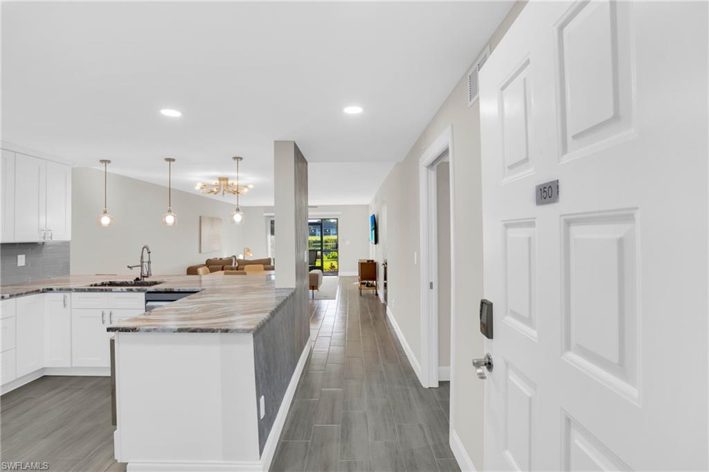 Kitchen with white cabinetry, light stone countertops, tasteful backsplash, a peninsula, and open floor plan