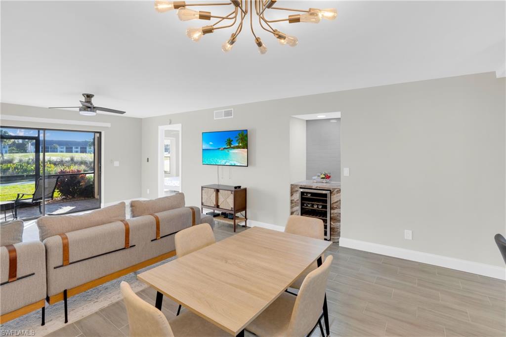 Dining area featuring wood tiled floors, a ceiling fan, a chandelier, and beverage cooler