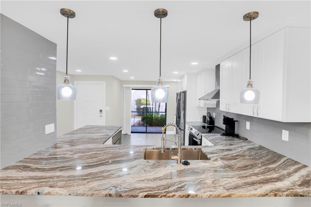 Kitchen with pendant lighting, a peninsula, decorative backsplash, white cabinets, and recessed lighting