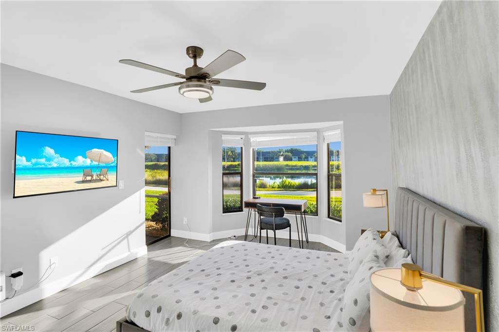 Bedroom featuring a water view, access to exterior, wood tiled floors, and a ceiling fan