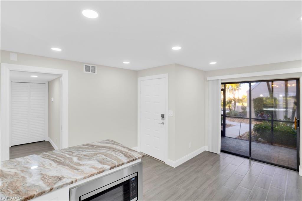 Kitchen featuring light stone counters, stainless steel microwave, recessed lighting, and wood tiled floors