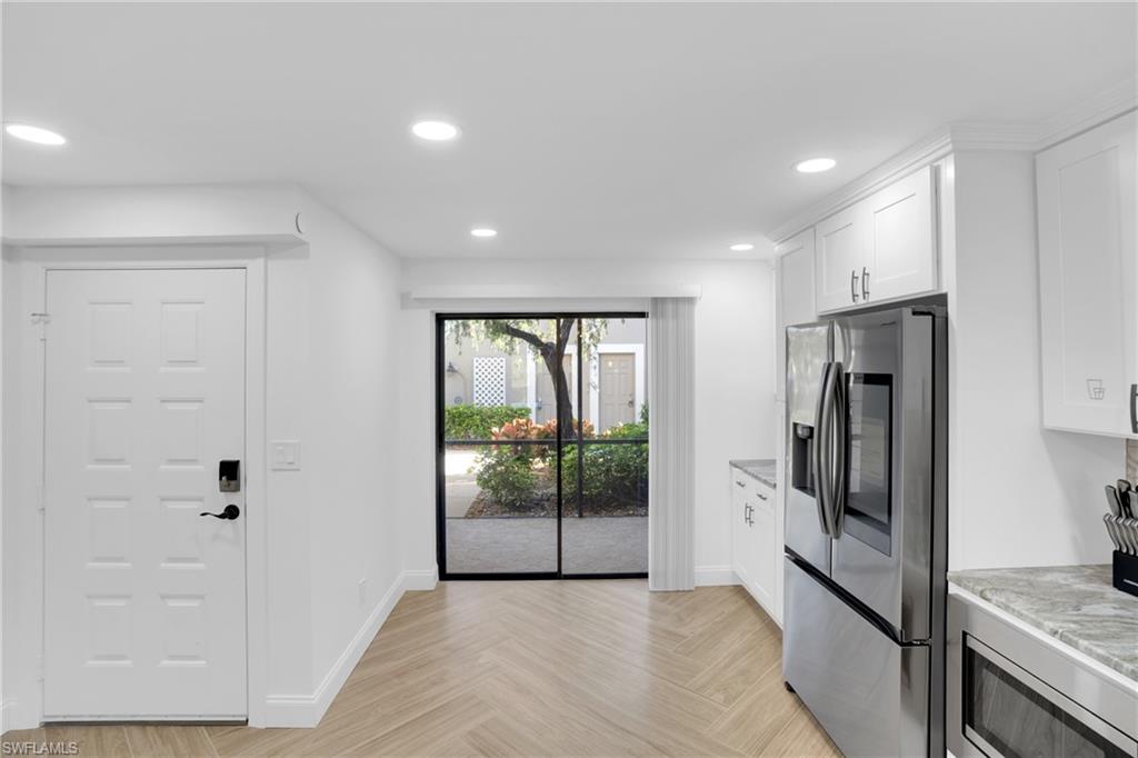 Kitchen with stainless steel appliances, white cabinets, recessed lighting, and light stone counters