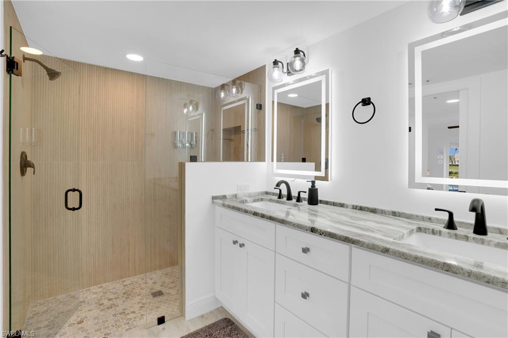 Bathroom with double vanity, a shower stall, and recessed lighting