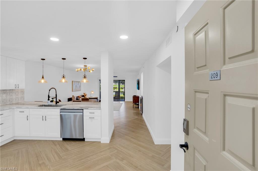 Kitchen featuring open floor plan, hanging light fixtures, white cabinetry, stainless steel dishwasher, and recessed lighting