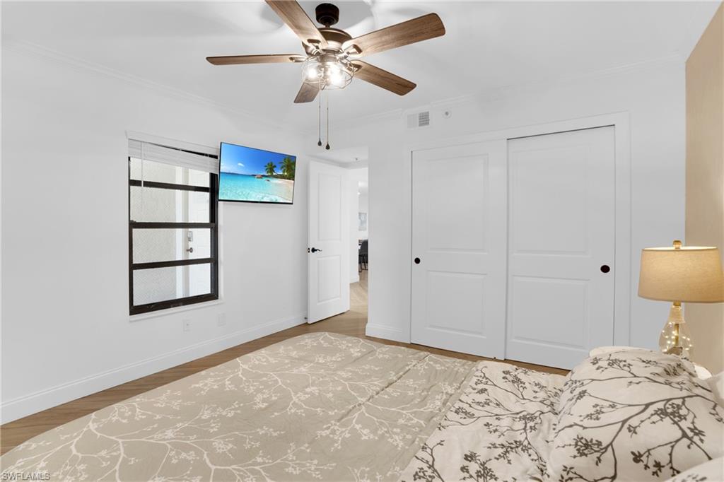 Bedroom with crown molding, ceiling fan, a closet, and light wood-type flooring