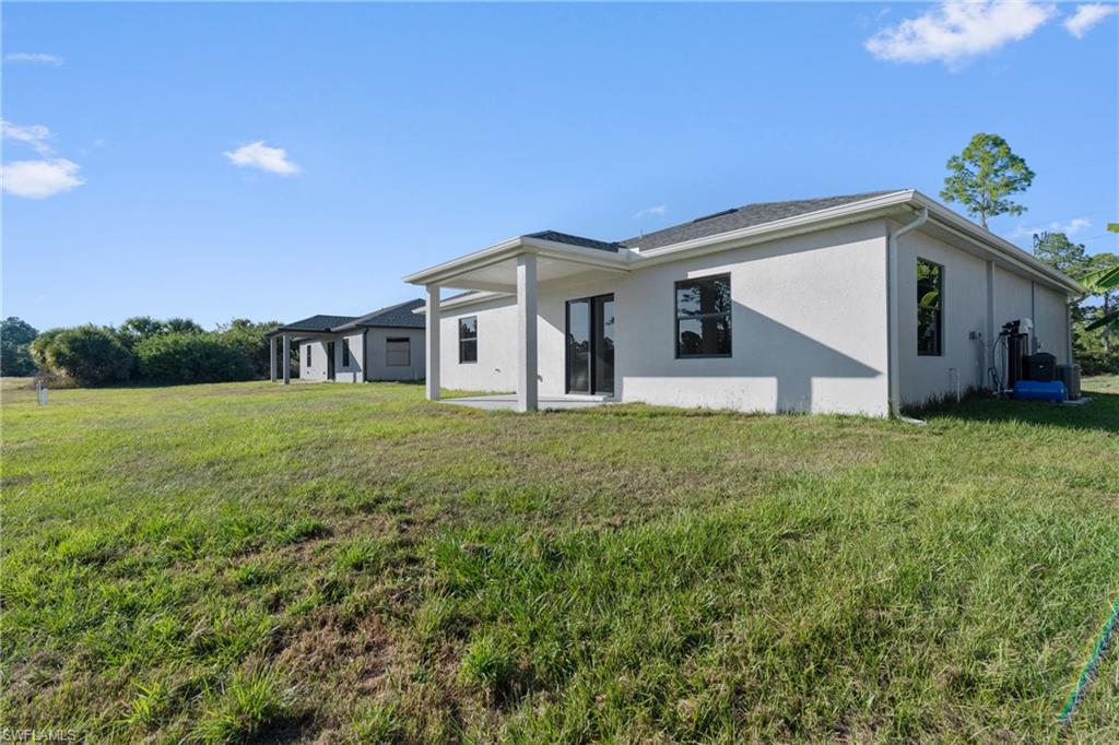 Rear view of property featuring stucco siding, a lawn, and a patio