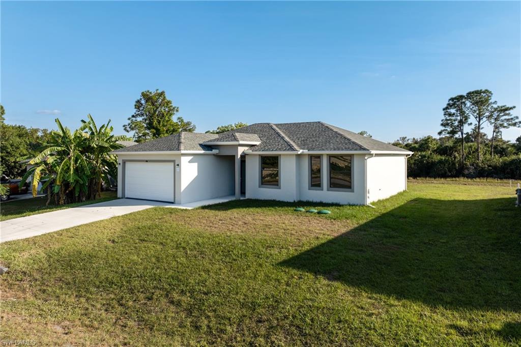 View of front of house with concrete driveway, a front yard, an attached garage, and stucco siding