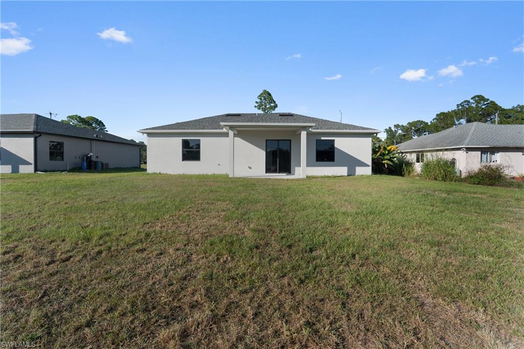 Rear view of house with a yard, a patio, and stucco siding
