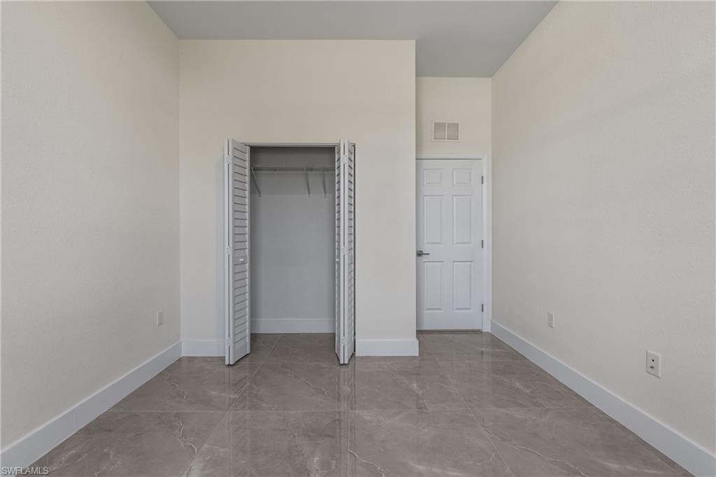 Unfurnished bedroom with a closet and marble tiled floors