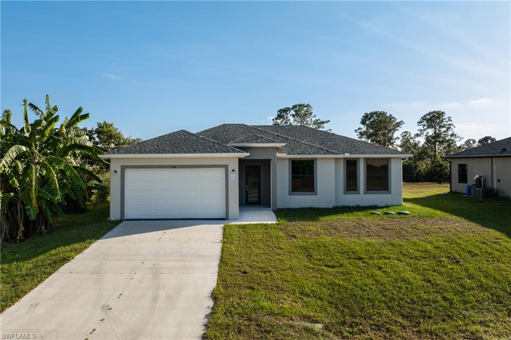 View of front of property featuring concrete driveway, stucco siding, a front lawn, and a garage