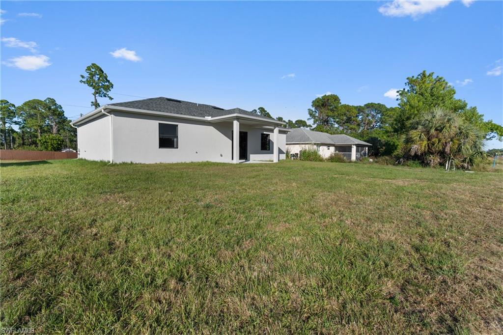 Rear view of property with a yard, stucco siding, and a patio