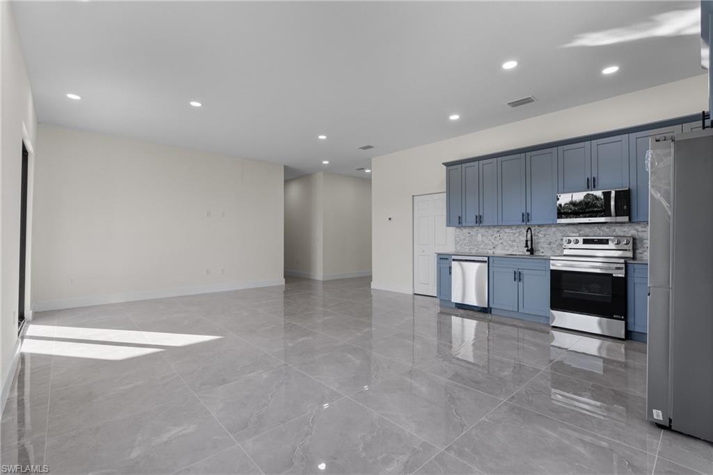 Kitchen with stainless steel appliances, recessed lighting, backsplash, light marble finish floors, and open floor plan
