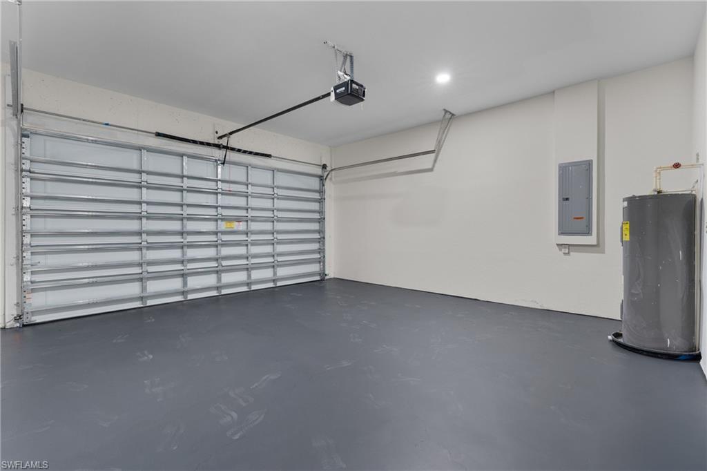 Garage featuring water heater, electric panel, and a garage door opener