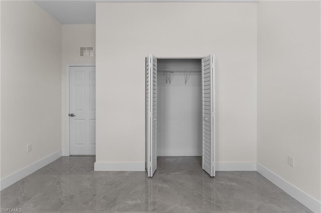 Unfurnished bedroom with a closet and finished concrete flooring