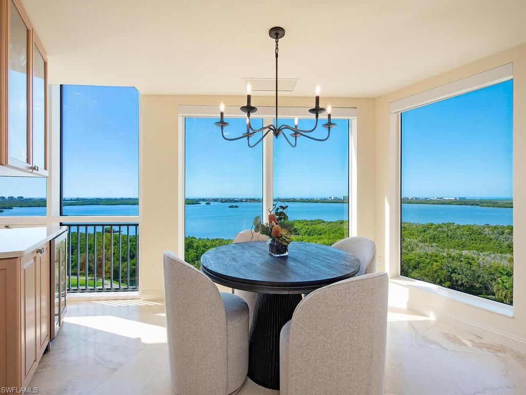 Great room dining with bar, featuring marble tiled flooring, a water view, healthy amount of natural light, and a chandelier