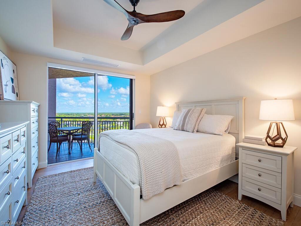 Bedroom with a tray ceiling, access to exterior, a ceiling fan, and oak wood floors