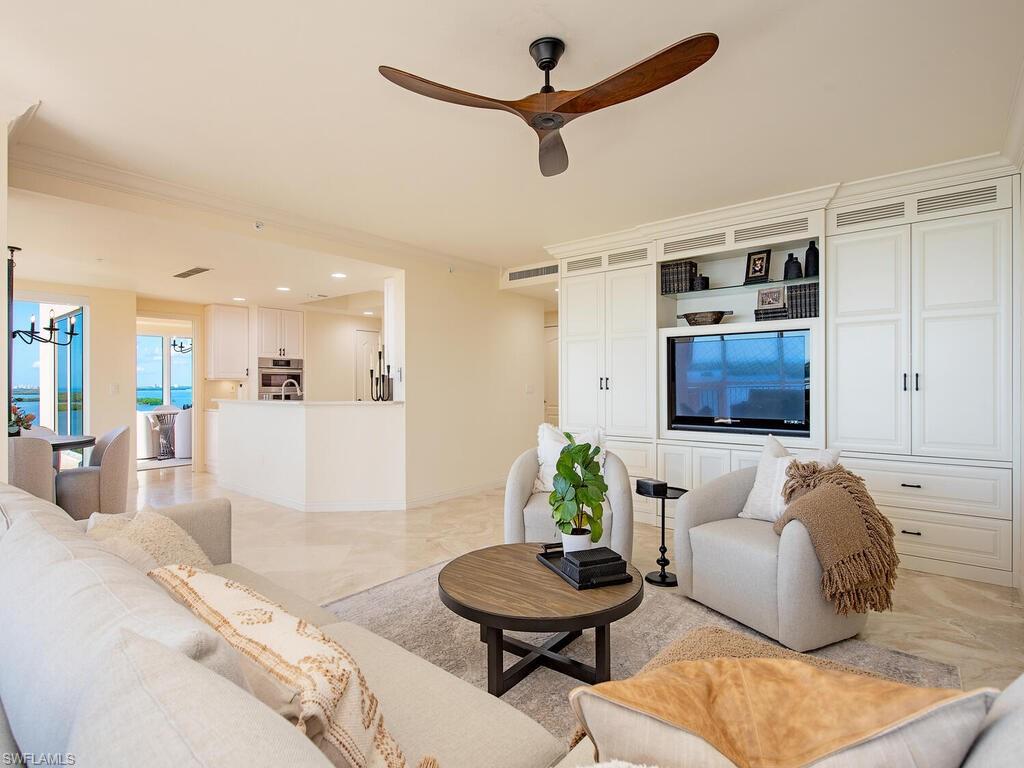 Living area with ceiling fan, a chandelier, and light marble finish floors