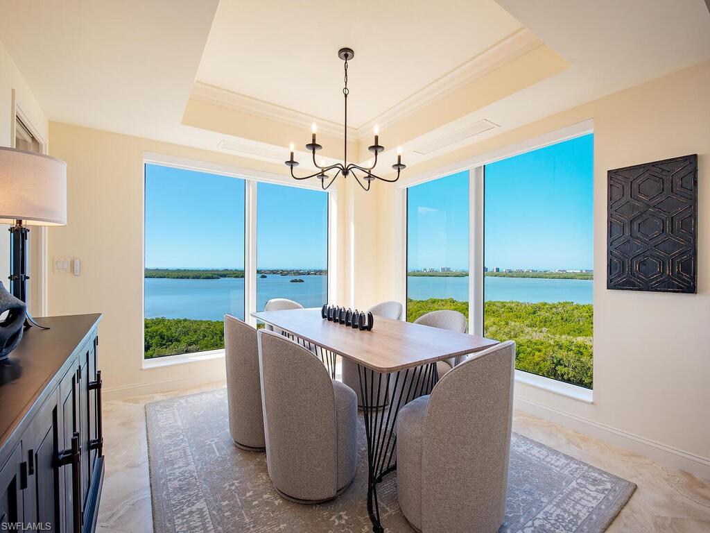 Dining area featuring healthy amount of natural light, a chandelier, a water view, and crown molding