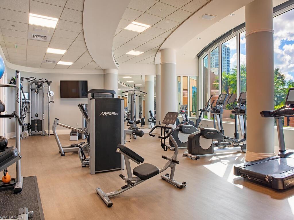 Workout area featuring a drop ceiling and a wall of windows