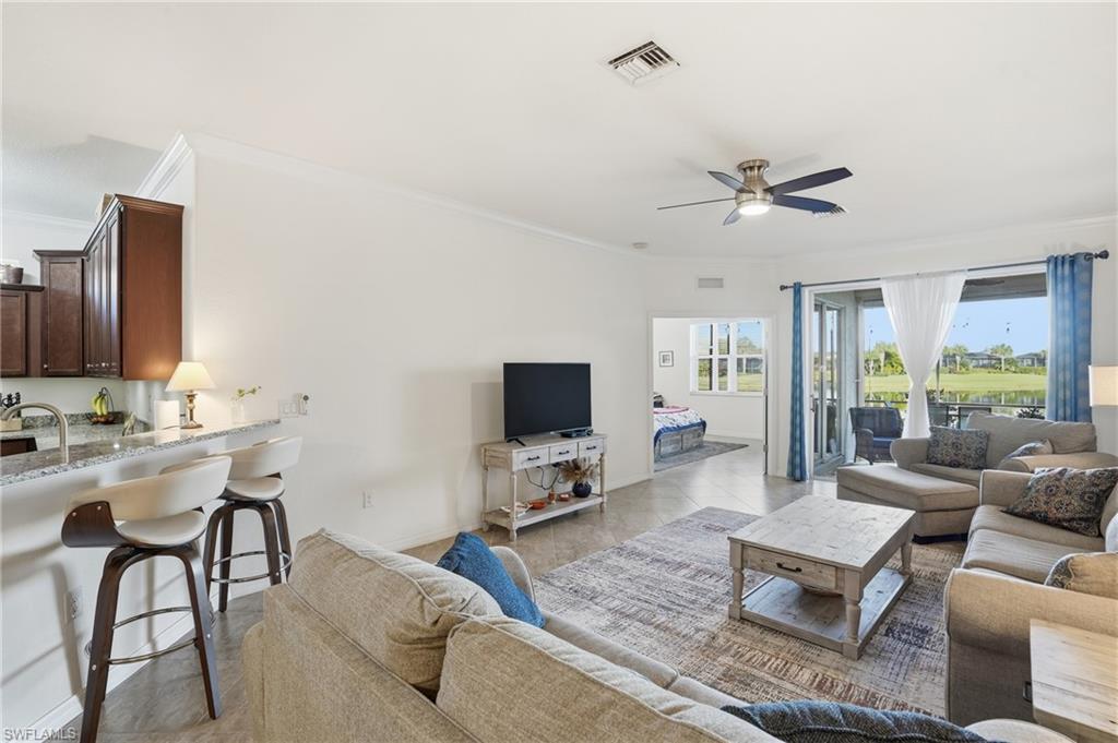 Living area featuring ornamental molding, ceiling fan, and light tile patterned floors