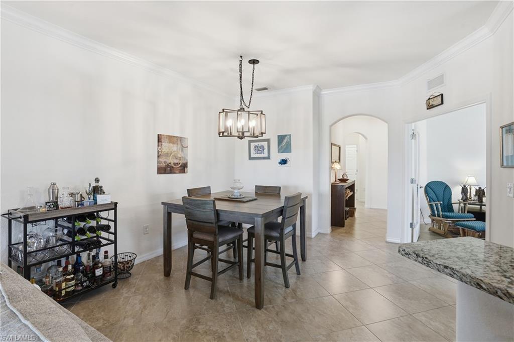 Dining area featuring arched walkways, crown molding, a chandelier, and light tile patterned floors